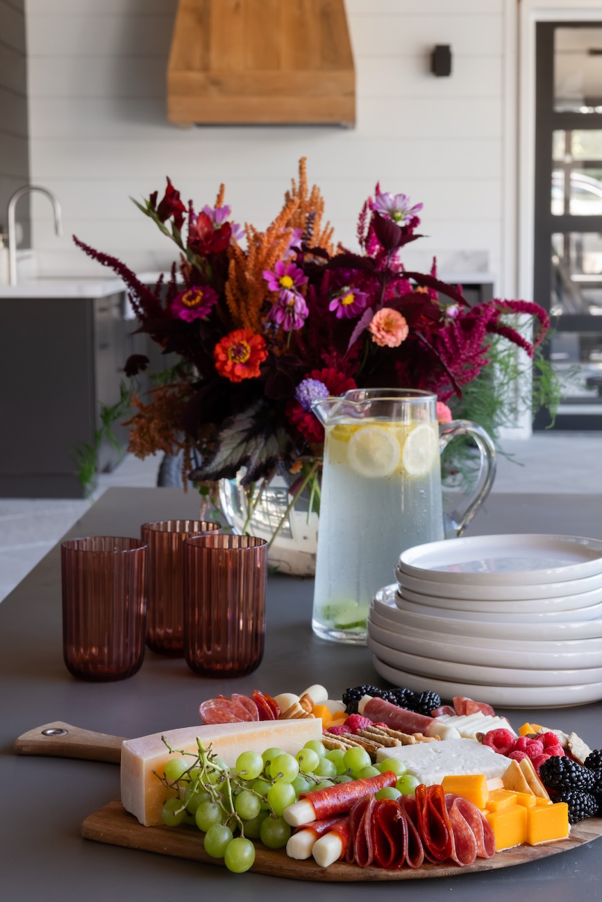 Stunning Outdoor Patio Table Set with Flowers Glasses, Plates, Cheese Plate, Water Pitcher | Milosi Landscaping