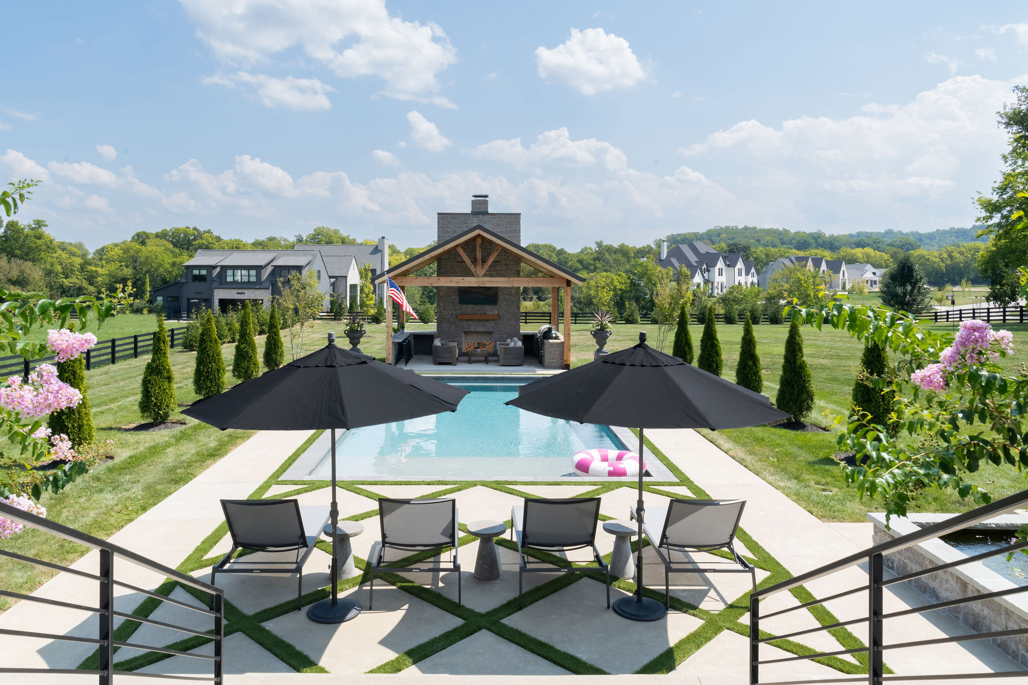 Long angle shot of custom pool facing well landscaped yard by Milosi.