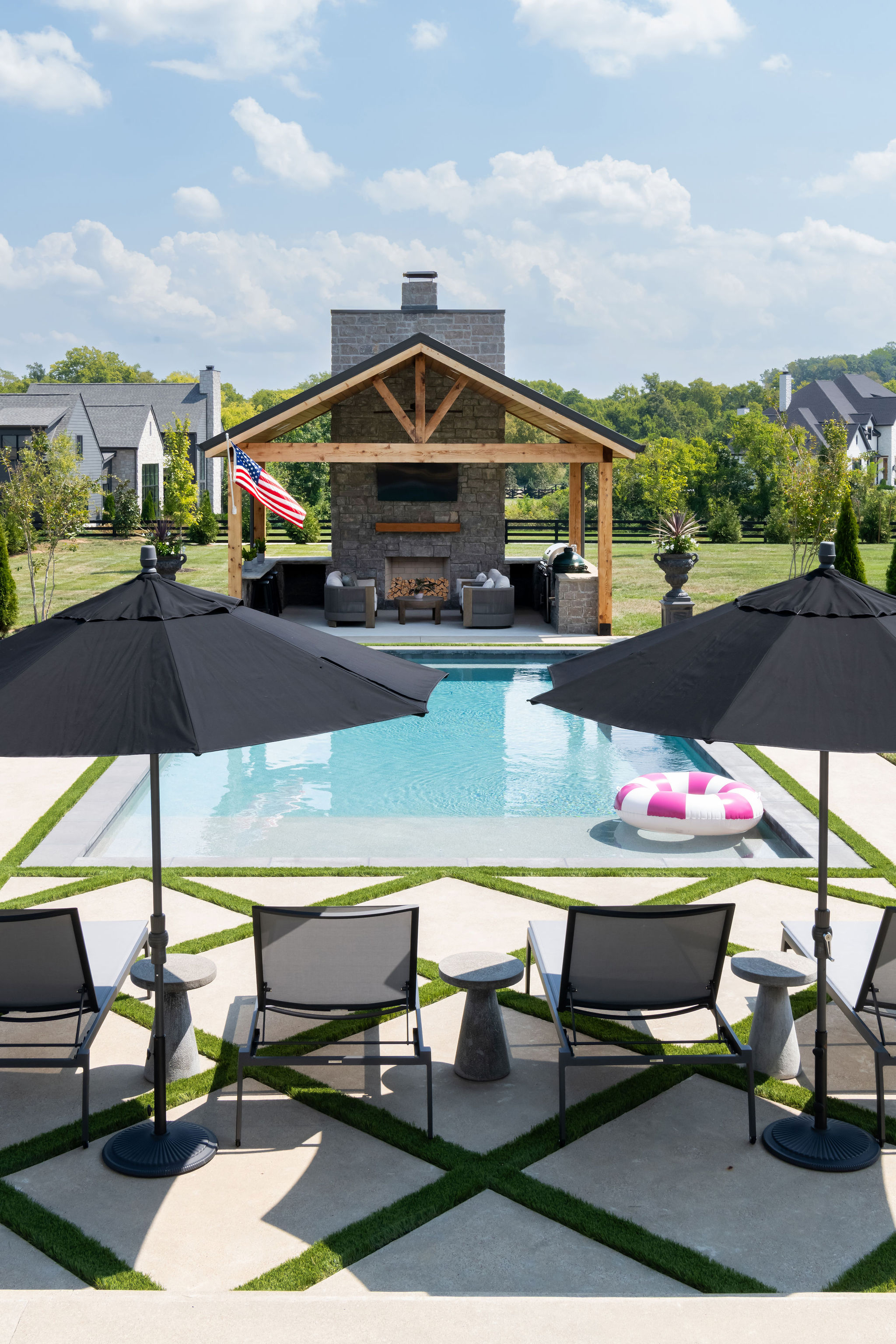 Patio chairs on new patio facing custom pool and pool house with outdoor kitchen.