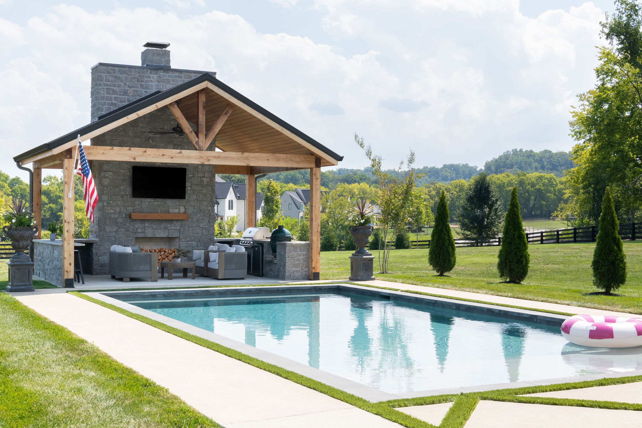 Outdoor kitchen and pool house with custom pool in foreground.