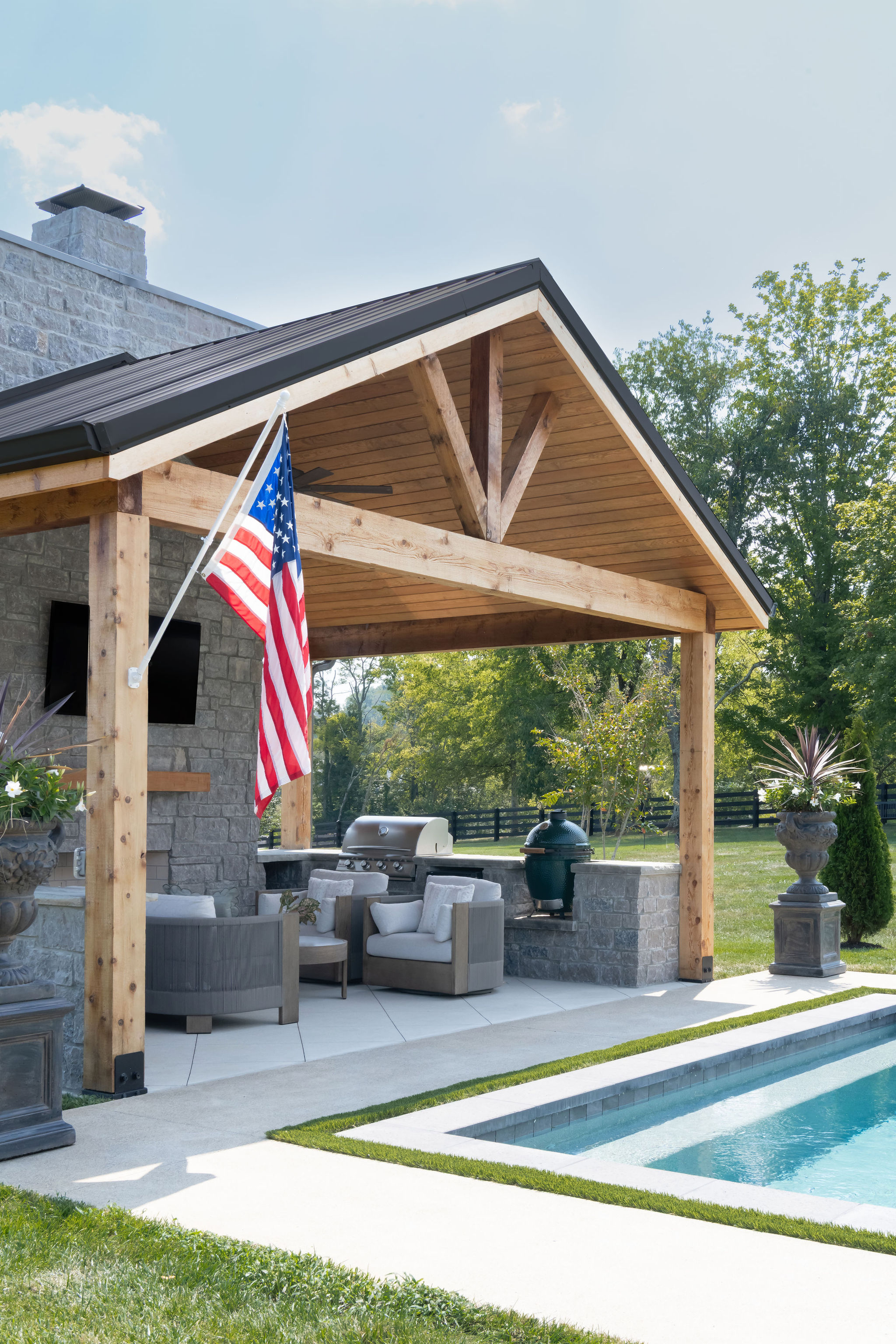 Side view of gray pool house with wood pergola built by Milosi Landscapes.