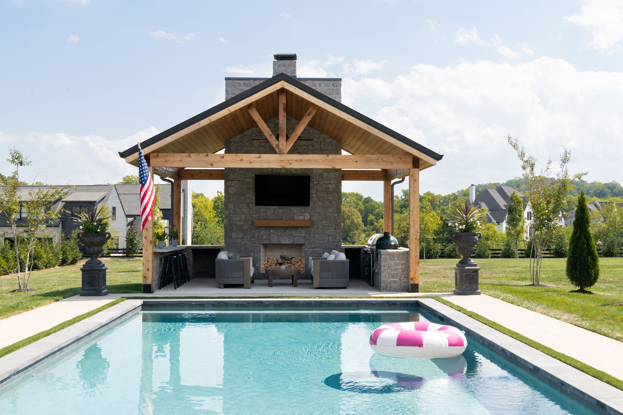 Close up of pool house with outdoor kitchen and custom pool in foreground.