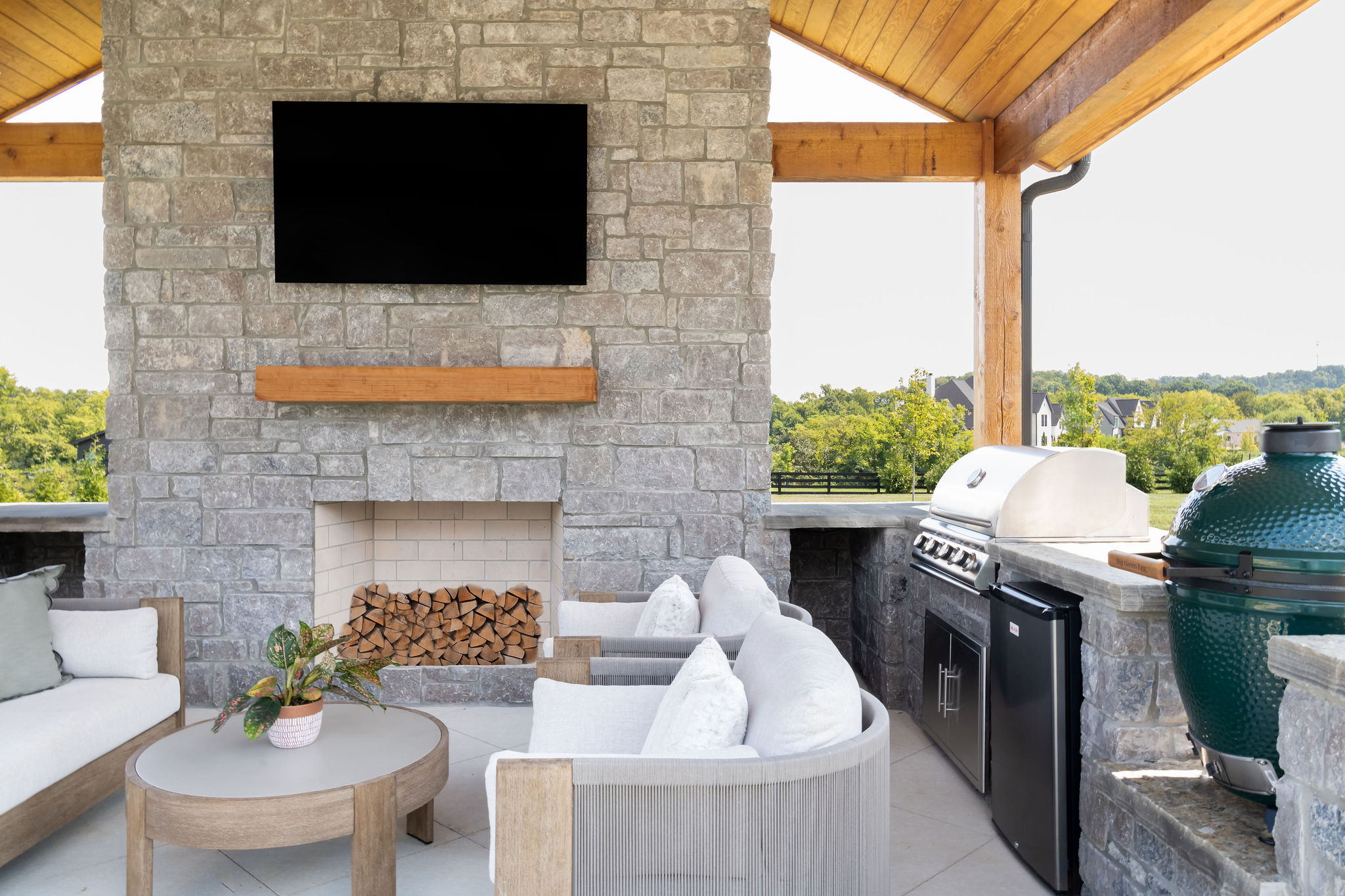 Straight view of fireplace and hearth with TV above the hearth as part of outdoor kitchen.