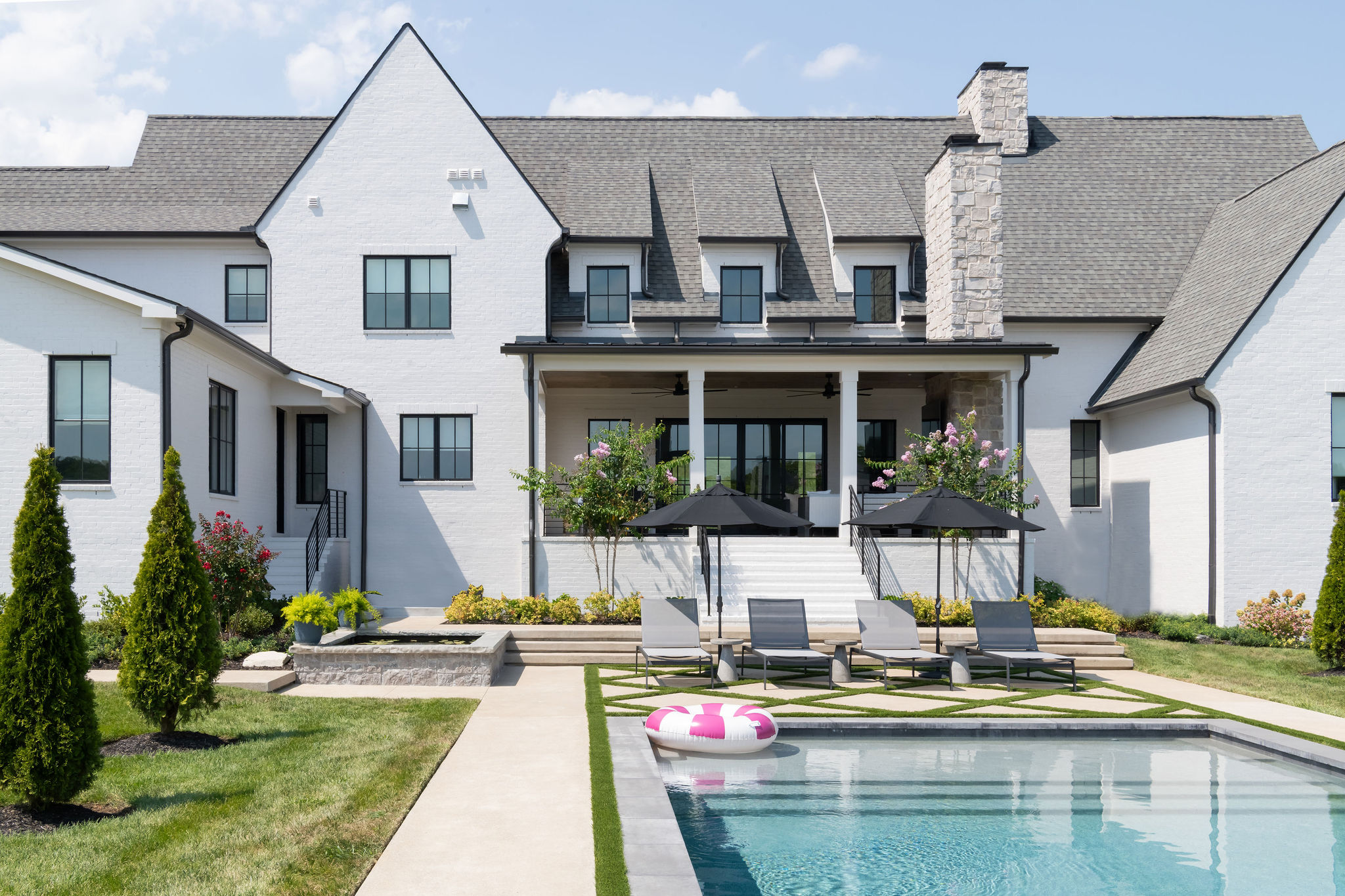 Large white home with custom pool in the foreground.
